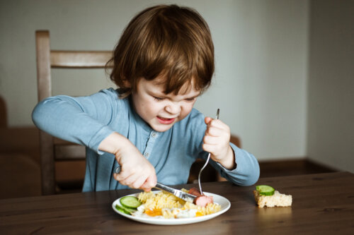 Criança comendo sem ter boas maneiras à mesa ainda.