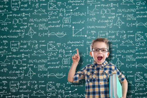 Niño con una pizarra llena de fórmulas matemáticas detrás de él.