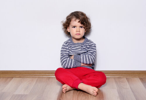 Niño sentado de brazos cruzados mostrando su negatividad ante la vida.