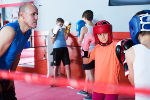Enfants pratiquant la boxe, l'un des sports de combat, avec leur entraîneur.