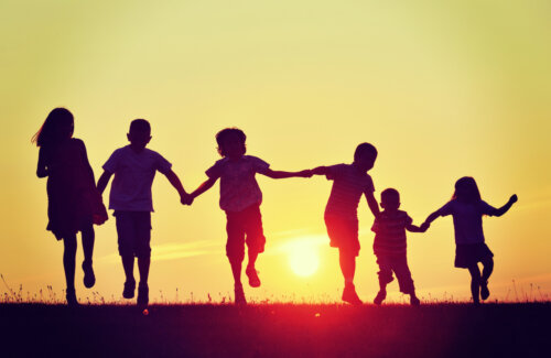 Niños agarrados de la mano en una puesta de sol.