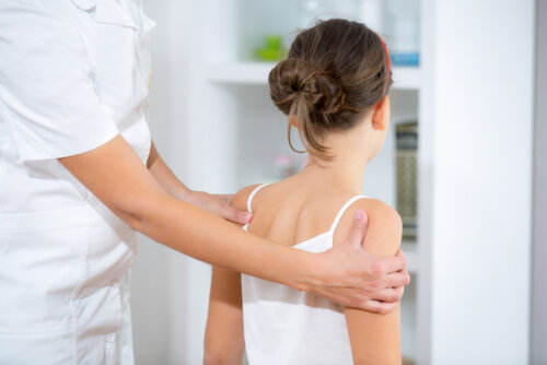 Chica con problemas de espalda en la consulta del médico durante la adolescencia.