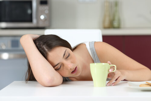 Adolescente medio dormida mientras se toma un café por la mañana.