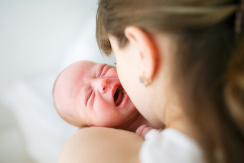 Un bébé qui pleure dans les bras de sa maman.