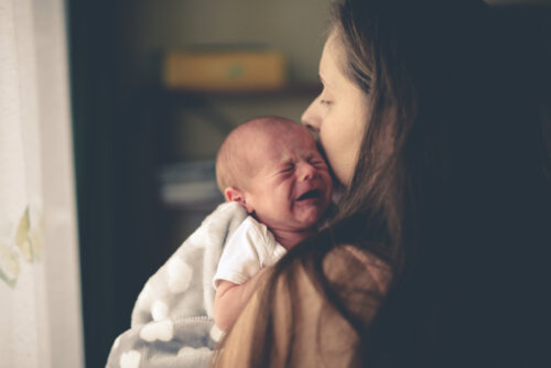 Bebé llorando mientras su madre lo abraza para evitar el síndrome del niño zarandeado.