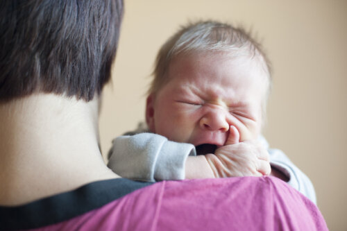 Bebé llorando en brazos de su padre.