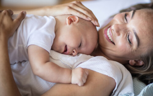 Madre abrazando a su bebé y sonriendo de felicidad durante el destete nocturno.