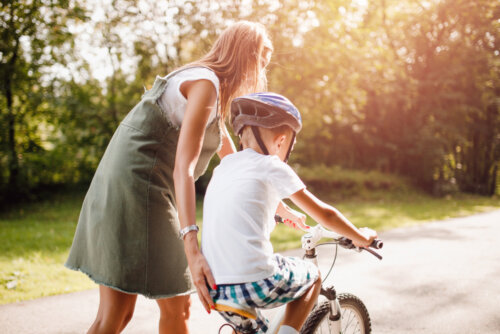 Madre ayudando a su hijo a montar en bicicleta.