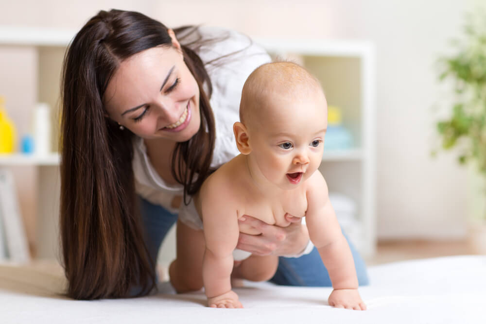 A mother helping her baby crawl.