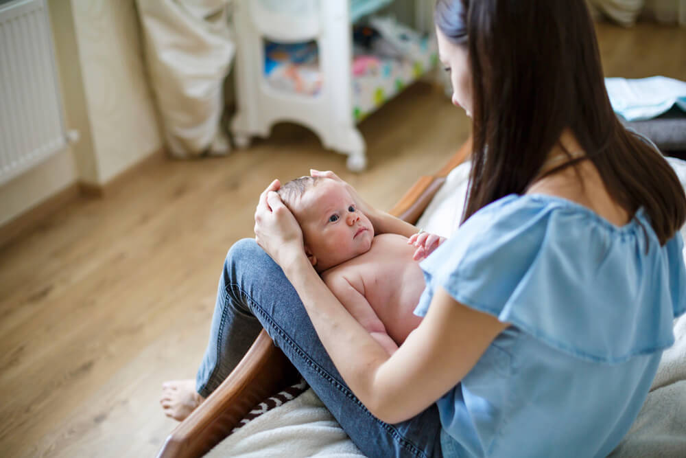 Mamá con su bebé apoyado entre las piernas.