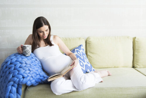 Mujer embarazada con retención de líquidos leyendo un libro sobre maternidad.