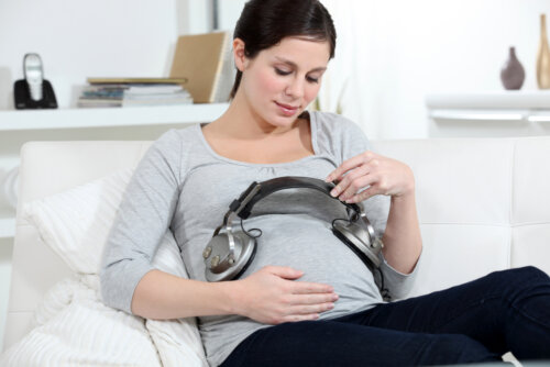 Mujer realizando una sesión de musicoterapia en casa durante su embarazo.