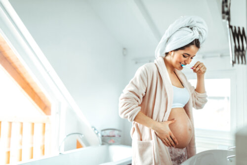 Mujer embarazada tras salir de la ducha cepillándose los dientes. Y tú, ¿cuándo te sentiste madre por primera vez?