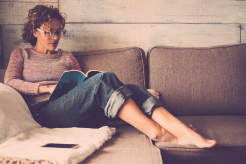Mujer leyendo uno de los libros de adultos nuevos en el sofá de casa durante la cuarentena.