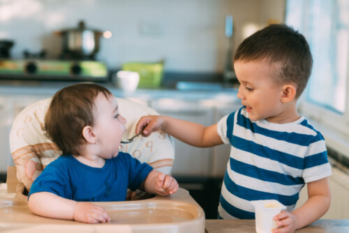 Niño dando de comer a su hermano pequeño.