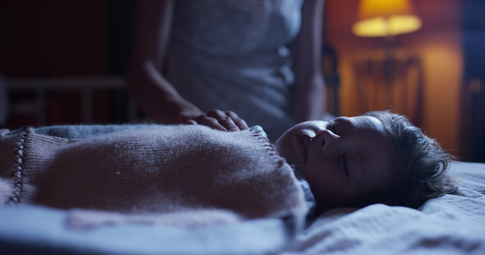 Niño durmiendo plácidamente en su cama por la noche.