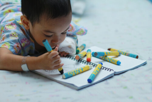 Un enfant qui dessine sur un lit d'hôpital;