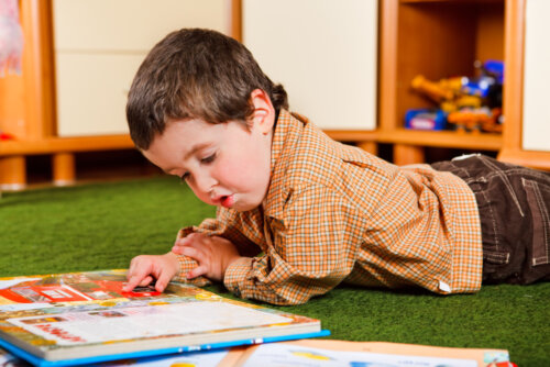 Niño leyendo en el suelo uno de los libros sobre las relaciones entre hermanos.