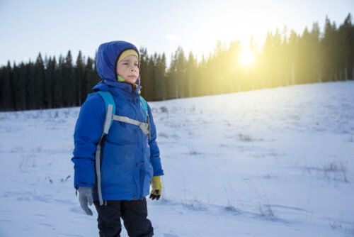 Niño en la nieve superando el frío y las adversidades gracias a la promoción de la resiliencia en la infancia.