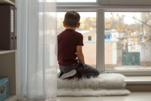 Niño TEA mirando por la ventana.