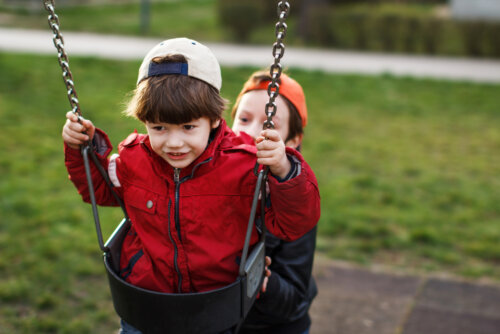 Niño columpiando a otro en el parque.