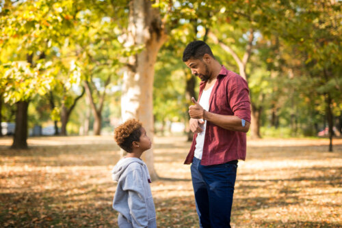 Padre hablando con su hijo sobre la disciplina positiva en el parque.