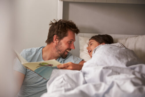 Padre leyendo uno de los libros de la Colección Iguales a su hija en la cama antes de dormir.