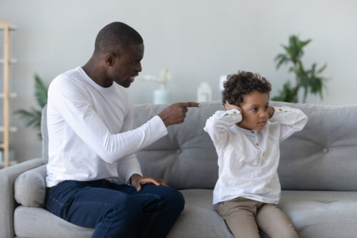 Padre regañando a su hijo intentando evitar gritar a su hijo.
