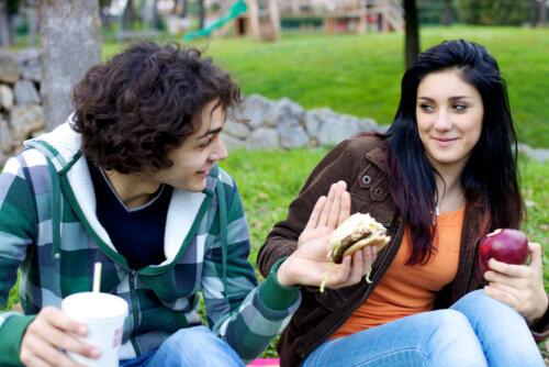Deux adolescents qui mangent dans un parc.