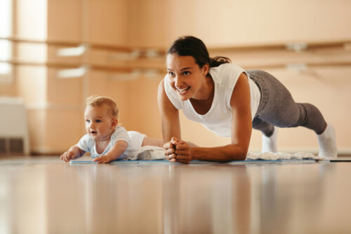 Bebé imitando a su madre mientras hace ejercicio.