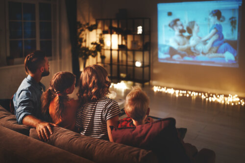 Familia viendo una película en casa a modo de cine.