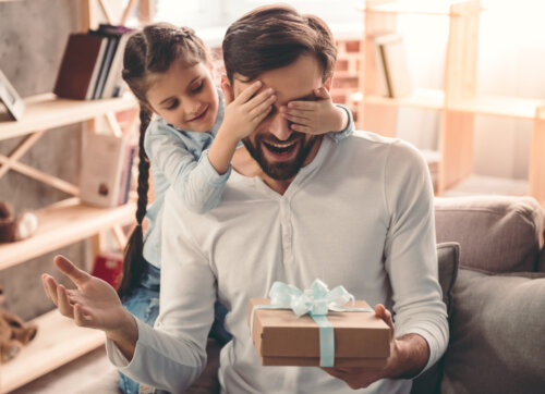 Niña haciéndole un regalo a su padre por el Día del Padre.