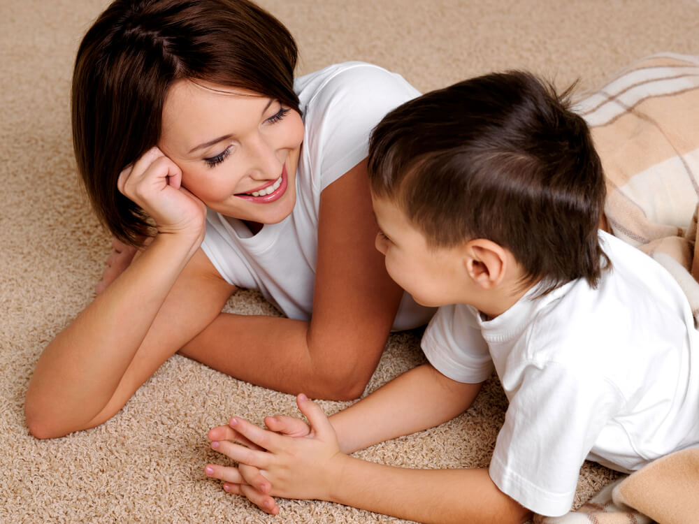 Mãe conversando com seu filho deitado no chão.