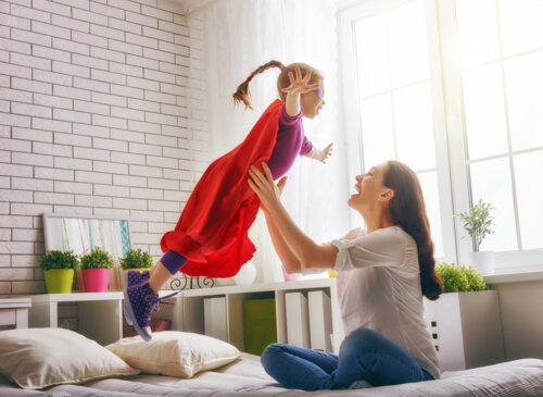 Madre cogiendo por lo aires a su hija vestida de superheroina.