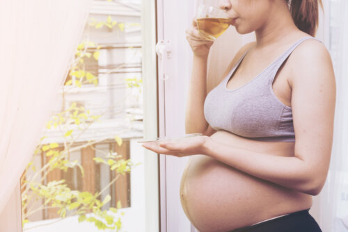 Mujer embarazada tomando una infusión para prevenir la retención del líquidos durante el embarazo.
