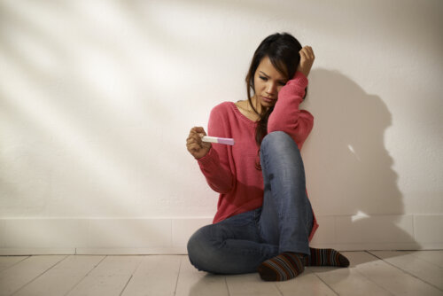 Mujer triste con un test de embarazo positivo porque no estaba planeado.