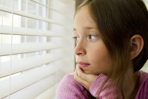 Niña mirando por la ventana durante la crisis de los seis años.