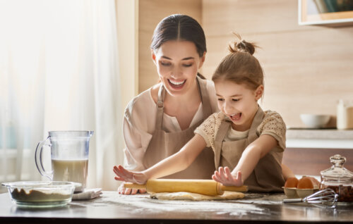 Madre con su niña ayudando en la cocina para ser una mamá divertida.