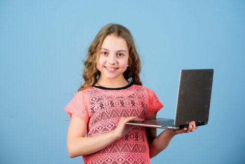 Niña con el ordenador en las manos preparada para sus clases en la escuela de inglés online.