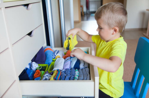 Un jeune garçon qui range ses vêtements dans son armioire.