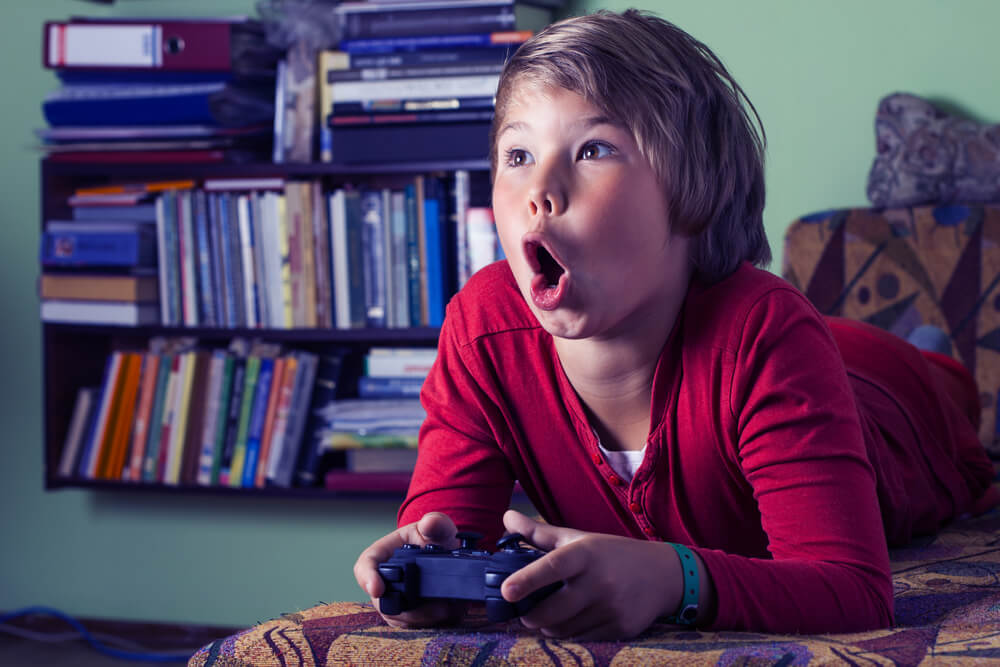 Niño jugando a videojuegos entusiasmado.