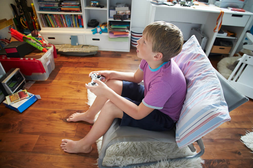 Niño jugando a videojuegos en casa.
