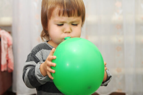 Niña soplando un globo para estimular el lenguaje.