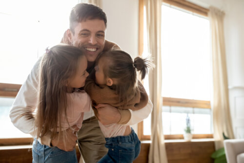 Padre abrazando a sus hijas debido a que tienen custodia compartida y se quedan en casa de mamá.