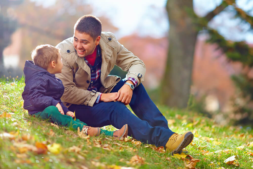 Padre hablando con su hijo en el parque estimulando su fluidez verbal.