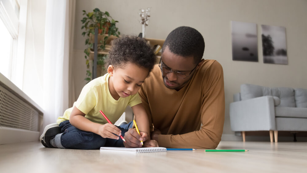 Père et fils jouent à des jeux avec du papier et un crayon à la maison.