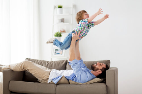 Padre implicado jugando con su hijo en el sofá.