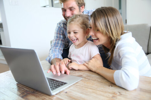 Padres con su hija viendo cuentacuentos online en el ordenador durante la cuarentena.