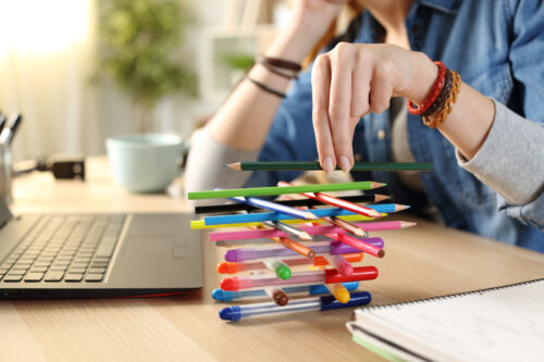 Adolescente aburrida jugando con los lápices de colores y sin hacer sus tareas.