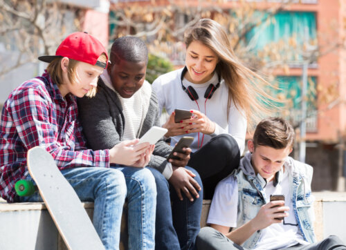 Adolescentes consultando las redes sociales en sus móviles.